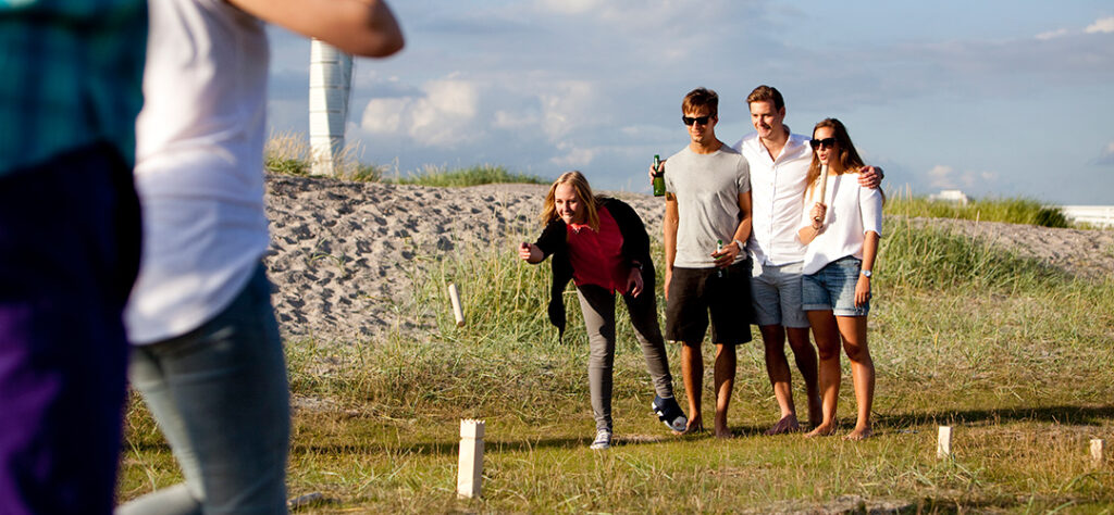 Teilnehmer beim Kubb-Turnier als Outdoor-Teamevent auf einer Wiese. Gemeinsam spielen sie das skandinavische Wurfspiel mit Holzklötzen.