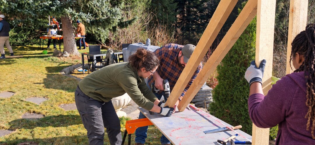 Team baut gemeinsam eine Holzkonstruktion beim Katapultbau im Freien.