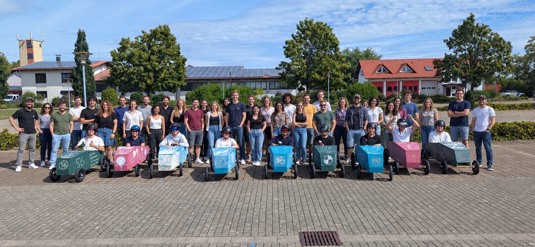 Team mit selbst gebauten Seifenkisten vor dem gemeinsamen Seifenkistenrennen