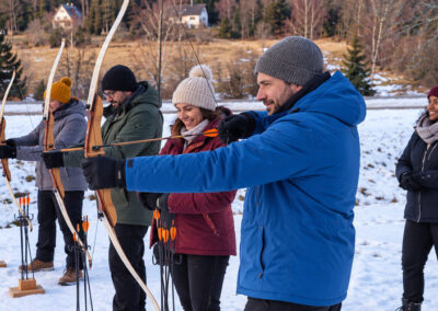 Team beim Bogenschießen während eines Winter-Challenge Teamevents im Schnee