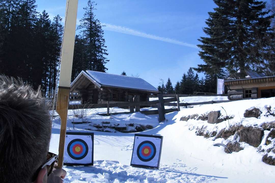 Teilnehmer zielt beim Bogenschießen auf zwei Zielscheiben im Schnee