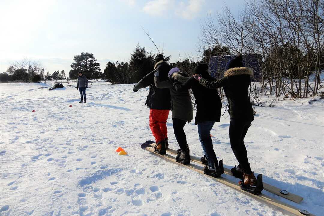 Teilnehmende bewältigen gemeinsam eine Team-Ski-Station der Winter-Challenge