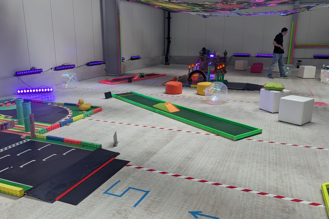 Indoor-Golf mit abwechslungsreichen, farbenfrohen Spielbahnen und kreativen Hindernissen in einer Veranstaltungshalle – wetterunabhängiger Spielspaß für Teamevents und Firmenveranstaltungen.